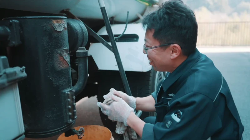 作業手袋を着けたスタッフが、車両の脇にある機器を確認している。